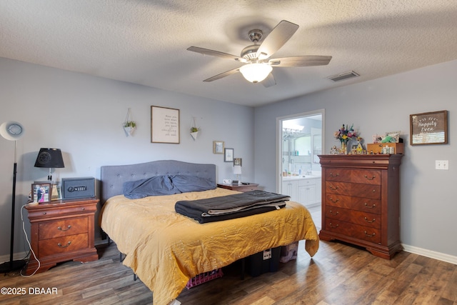 bedroom with ceiling fan, dark wood-type flooring, connected bathroom, and a textured ceiling