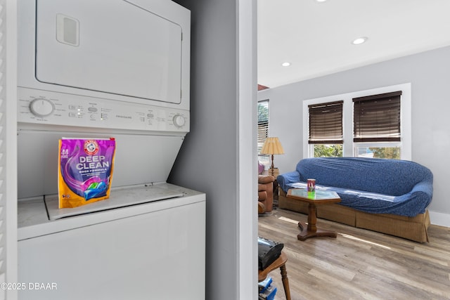 laundry area featuring laundry area, baseboards, wood finished floors, stacked washing maching and dryer, and recessed lighting