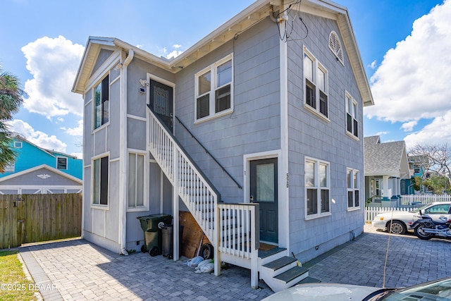 view of front of property with a patio, stairway, and fence