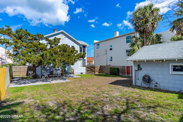 view of yard featuring a gate, a fenced backyard, and a patio