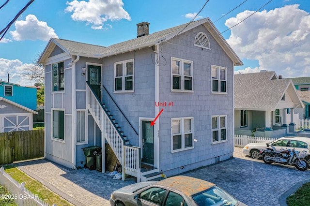 view of front facade with stairs, fence, a chimney, and a patio