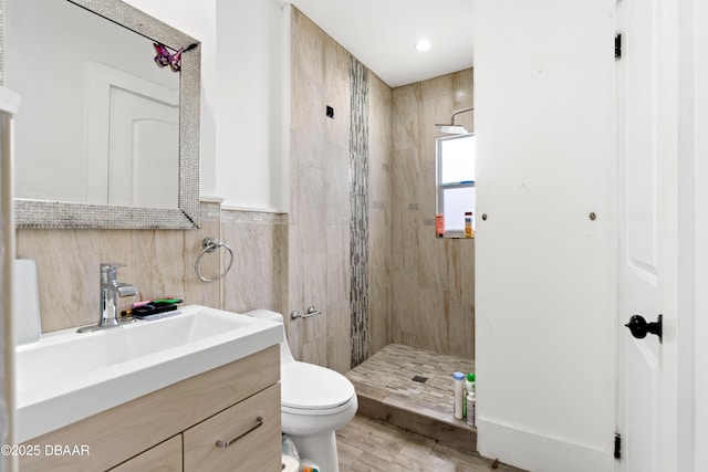 full bath with toilet, tile walls, a shower stall, and vanity