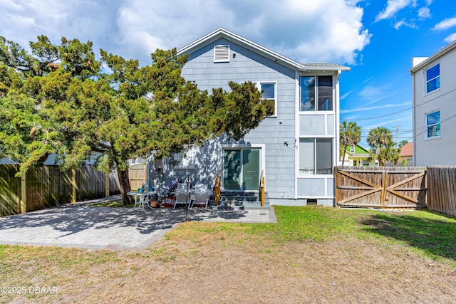 rear view of property featuring a yard, a fenced backyard, a gate, and a patio