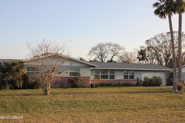 ranch-style house featuring a garage, brick siding, and a lawn