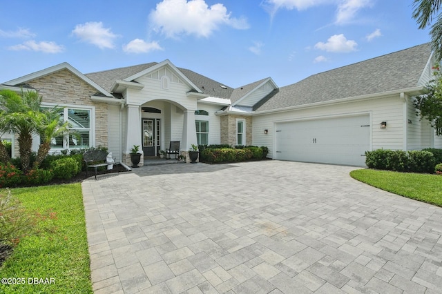 3236 Modena Way, New Smyrna Beach, FL 32168 - view of front of home featuring stone siding, decorative driveway, a garage, and a shingled roof