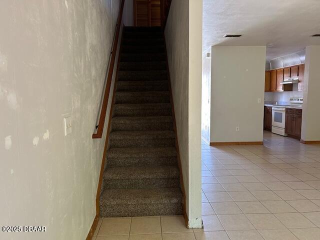 staircase with visible vents, baseboards, and tile patterned flooring