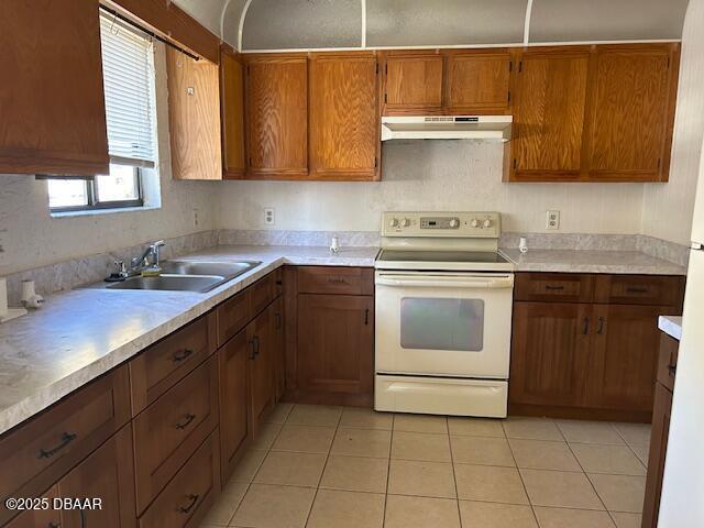 kitchen featuring white electric range oven, a sink, light countertops, under cabinet range hood, and brown cabinets