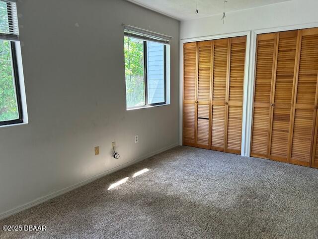 unfurnished bedroom with multiple closets and carpet flooring