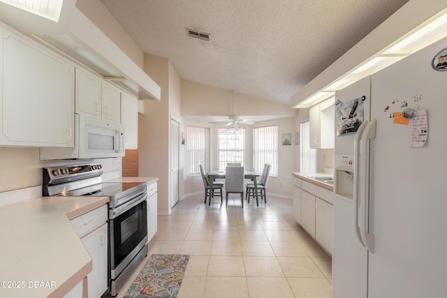 kitchen with lofted ceiling, light tile patterned flooring, white appliances, visible vents, and light countertops