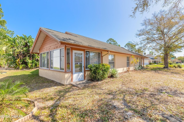 back of property with a sunroom and stucco siding