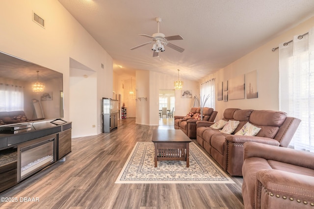 living area with lofted ceiling, visible vents, a textured ceiling, wood finished floors, and ceiling fan with notable chandelier