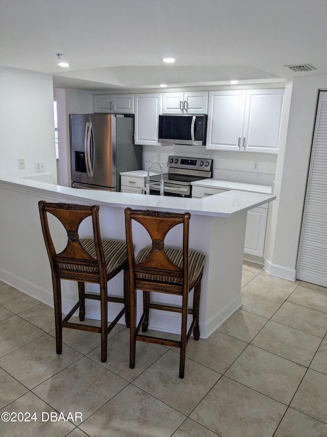 kitchen featuring stainless steel appliances, white cabinets, and a kitchen bar