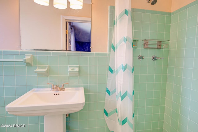 bathroom with a shower with shower curtain, tile walls, and sink