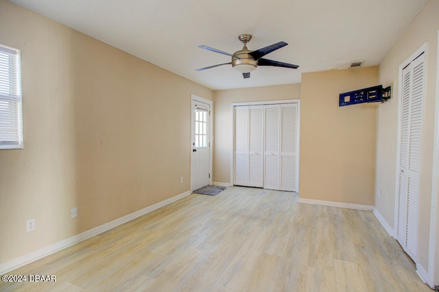 unfurnished bedroom featuring ceiling fan, light hardwood / wood-style flooring, and two closets