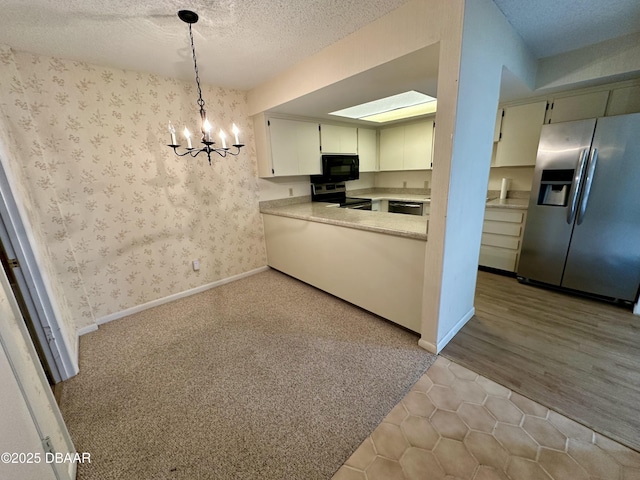 kitchen with wallpapered walls, an inviting chandelier, stainless steel appliances, light countertops, and a textured ceiling