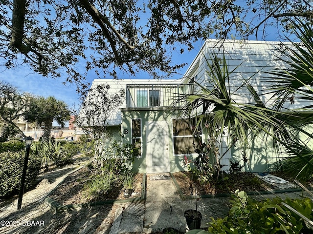 back of house featuring a balcony and stucco siding