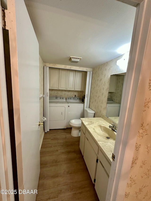 bathroom with visible vents, toilet, wood finished floors, wallpapered walls, and vanity