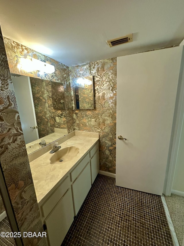 bathroom featuring vanity, visible vents, baseboards, wallpapered walls, and tile patterned flooring