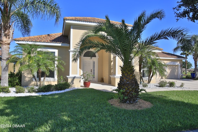 mediterranean / spanish house featuring a front yard and a garage