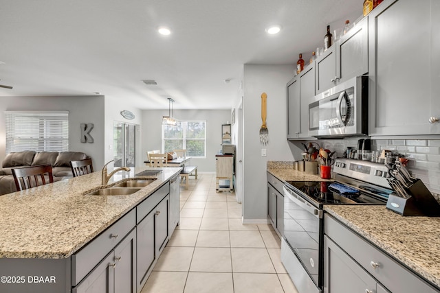 kitchen featuring appliances with stainless steel finishes, gray cabinets, a sink, and open floor plan