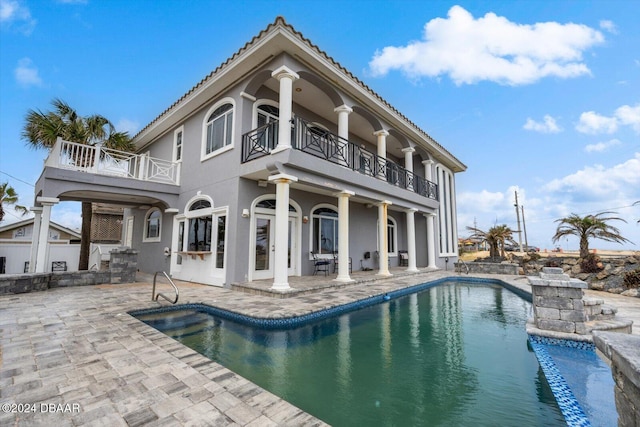 back of property with a balcony, an outdoor bar, and a patio