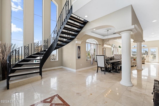 stairs featuring ornate columns, a healthy amount of sunlight, and a towering ceiling