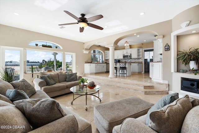 living room with ceiling fan and ornate columns