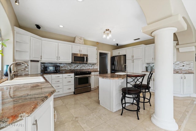 kitchen with white cabinetry, appliances with stainless steel finishes, sink, and dark stone counters