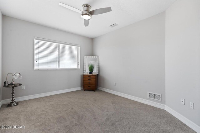 carpeted spare room featuring ceiling fan