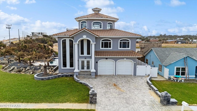 mediterranean / spanish-style house featuring a garage, a front lawn, and french doors