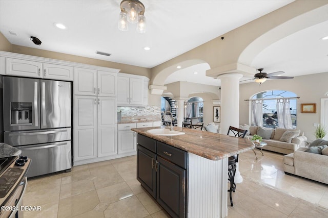 kitchen featuring white cabinetry, sink, stainless steel fridge, and a breakfast bar