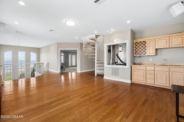 kitchen with light brown cabinetry, sink, decorative light fixtures, and wood-type flooring