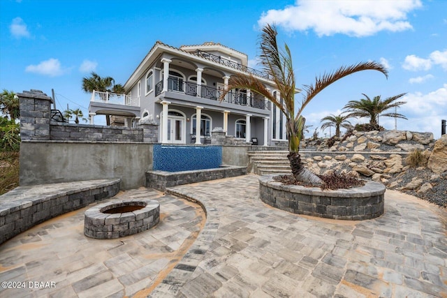 view of patio with a balcony and an outdoor fire pit