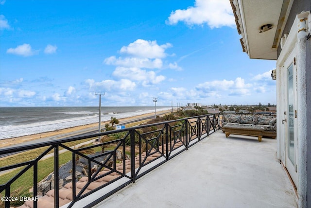 balcony featuring a view of the beach and a water view