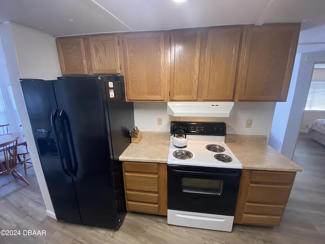 55705 Keith St, Astor, FL 32102 - kitchen featuring range hood, light countertops, black fridge with ice dispenser, range with electric cooktop, and light wood finished floors