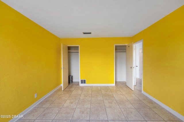 unfurnished bedroom with multiple closets and light tile patterned floors