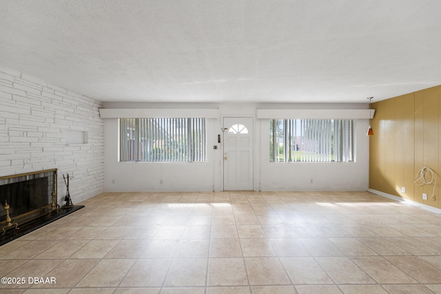 unfurnished living room with light tile patterned floors, a fireplace, a textured ceiling, and wood walls