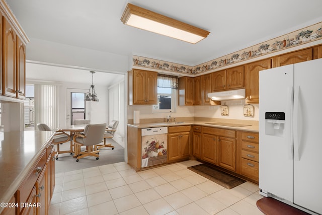 kitchen with a wealth of natural light, white appliances, hanging light fixtures, and sink