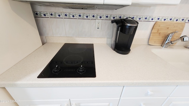 2700 N Atlantic Ave Unit 918, Daytona Beach, FL 32118 - detailed view of black electric cooktop, light countertops, decorative backsplash, white cabinets, and a sink