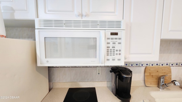 2700 N Atlantic Ave Unit 918, Daytona Beach, FL 32118 - detailed view of white microwave, a sink, tasteful backsplash, white cabinets, and light countertops