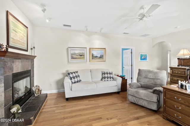 living room featuring a fireplace, light hardwood / wood-style floors, and ceiling fan