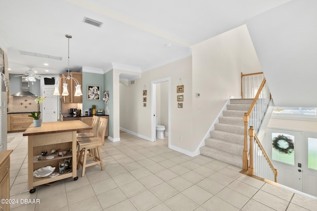 kitchen featuring butcher block countertops, crown molding, wall chimney range hood, backsplash, and decorative light fixtures