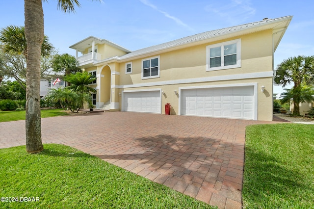 view of front of property with a garage, a front lawn, and a balcony