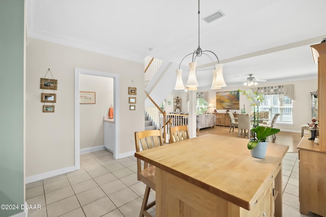 tiled dining area featuring ceiling fan with notable chandelier and crown molding