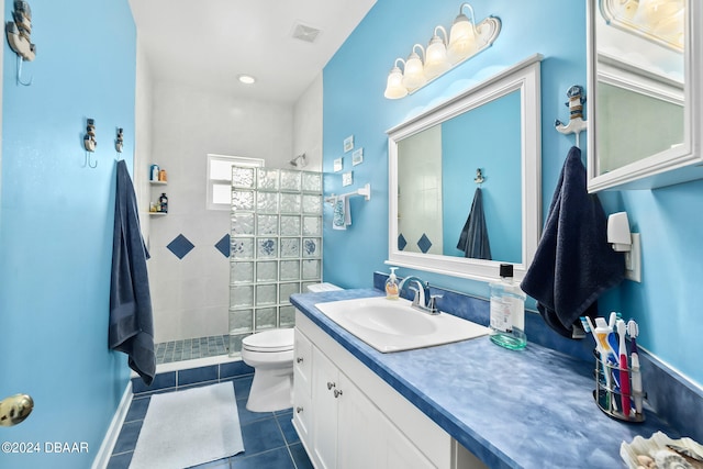 bathroom featuring toilet, vanity, tile patterned floors, and a tile shower