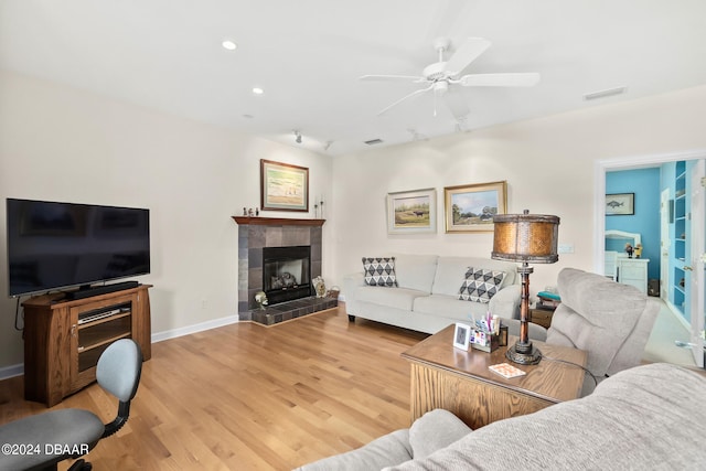 living room with ceiling fan, wood-type flooring, and a fireplace