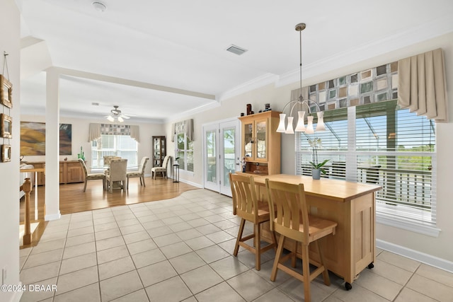 tiled dining space featuring ornamental molding and ceiling fan with notable chandelier