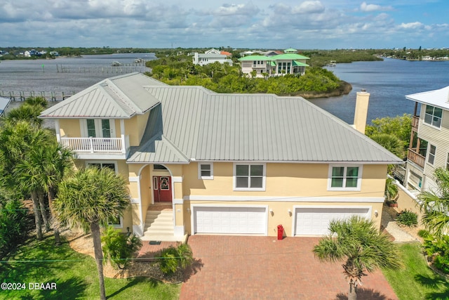 view of front facade with a balcony, a garage, and a water view