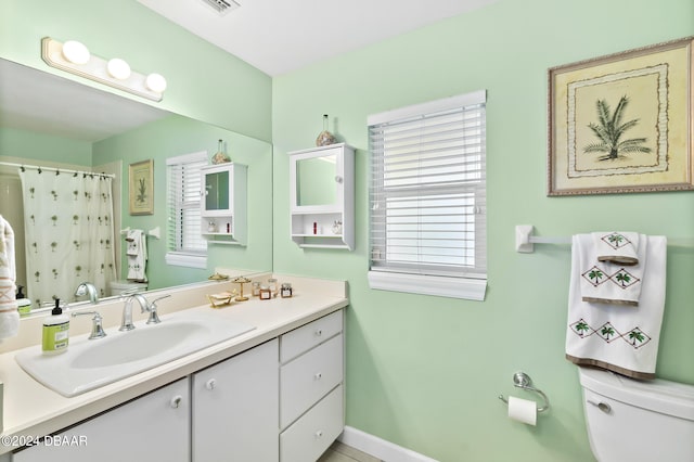 bathroom with toilet, vanity, a wealth of natural light, and curtained shower