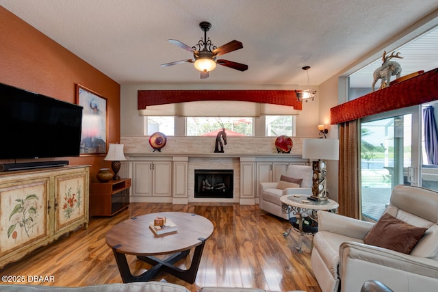 3102 N Springwater Ct N, Port Orange, FL 32128 - living area featuring light wood-style floors, a ceiling fan, a textured ceiling, and a fireplace